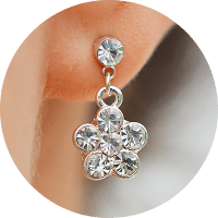 Silver earring with clear gemstones on a blurred background