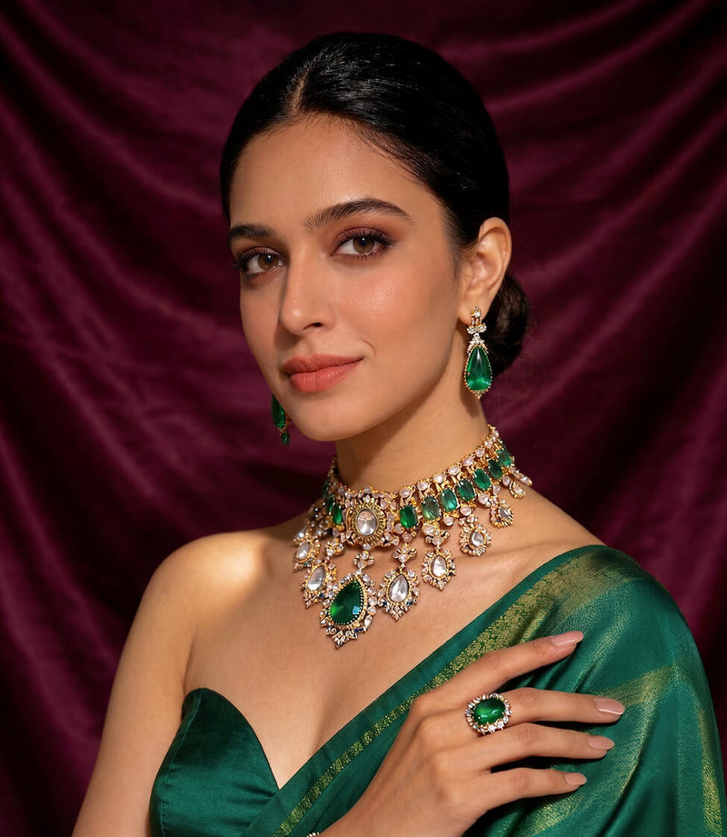 Woman wearing a green saree with jewelry against a purple curtain background